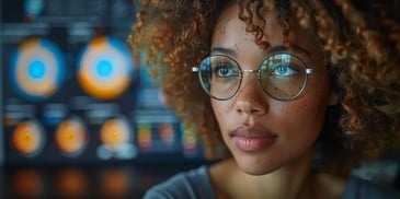 Woman with glasses and curly hair analyzing data.