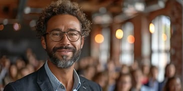 Smiling man with glasses in a crowded room.