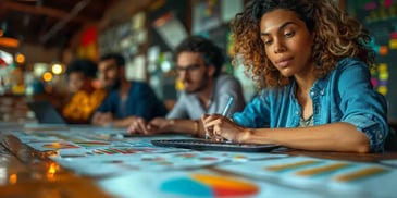 Focused woman with curly hair working on financial charts in a collaborative workspace.