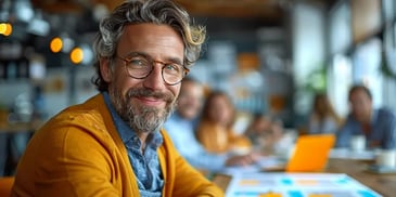 Smiling man with glasses in a meeting.