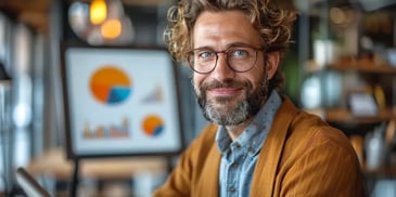 Smiling man with glasses in front of charts.