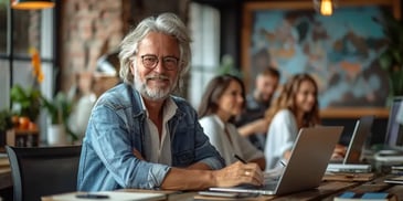 Smiling older man with glasses using laptop.