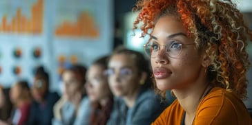 Woman with curly hair and glasses attentively listening.