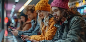 Young people in winter clothes using phones.