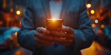 Man holding glowing smartphone at night.