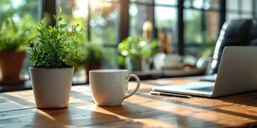 Potted plant and white coffee mug on a wooden desk.