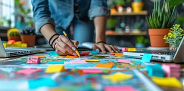 Person writing on sticky notes over maps.